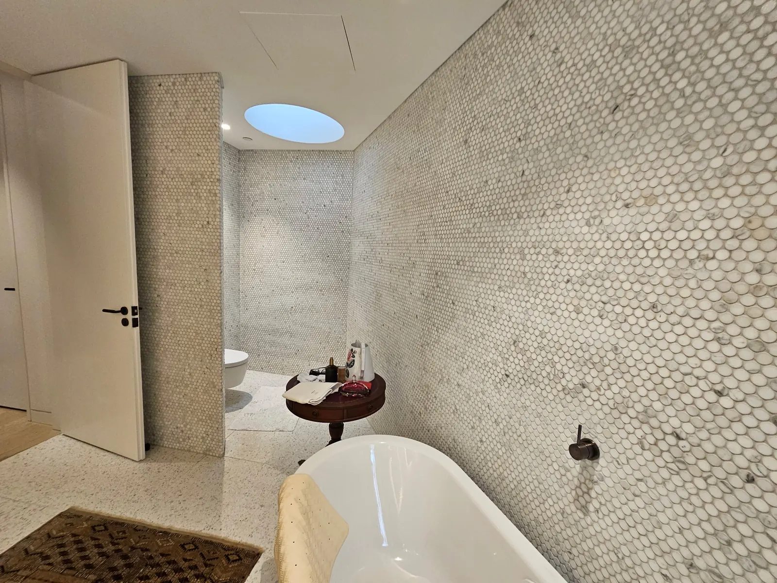 Finished bathroom with penny-round mosaic walls and a freestanding bath