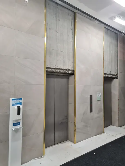 Large-format porcelain wall tiles with brass trims in a commercial lift lobby