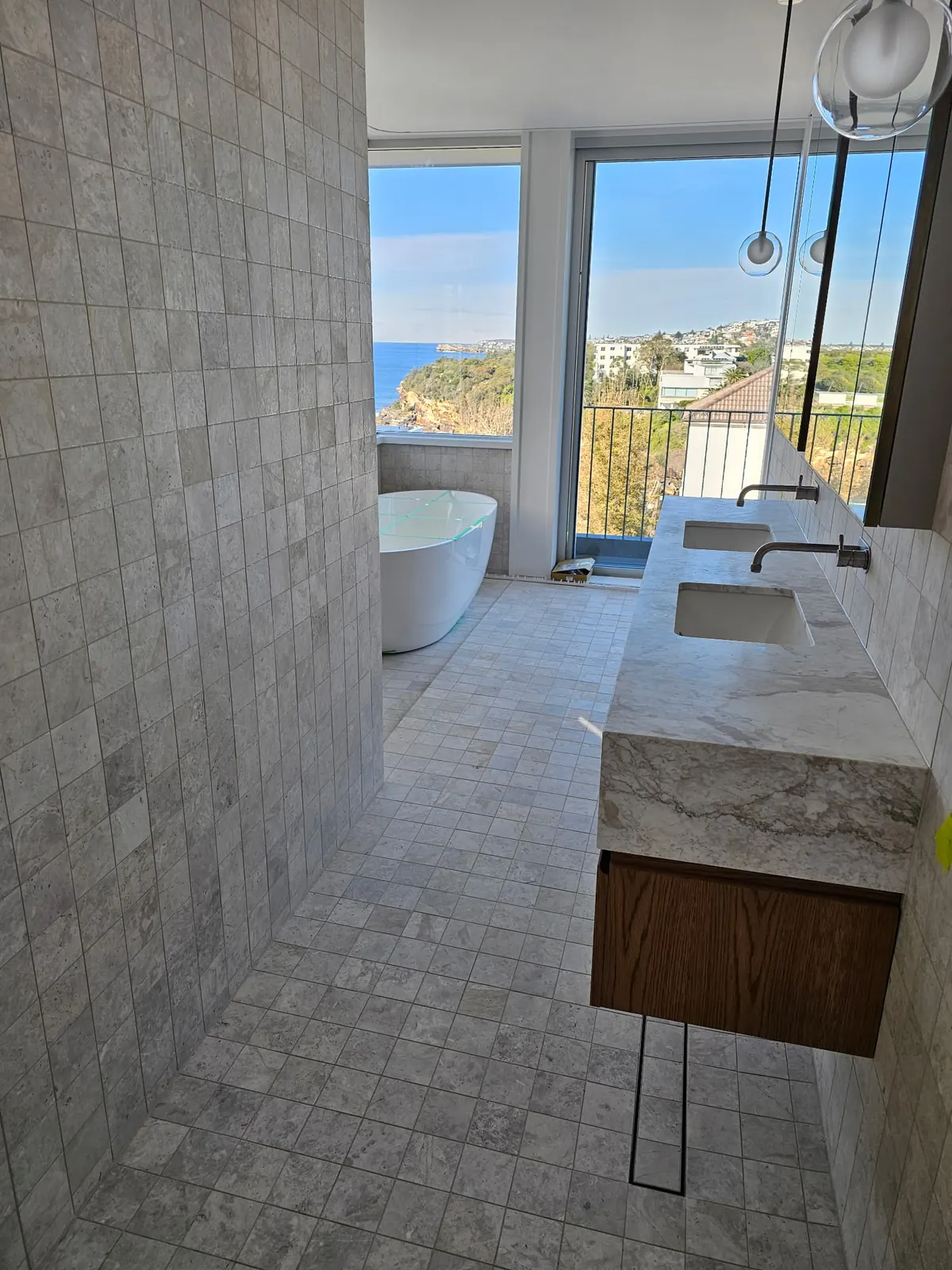 Tiled ensuite with a freestanding bath and coastal views