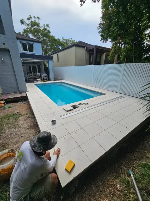 Laying pool surround tiles in a backyard