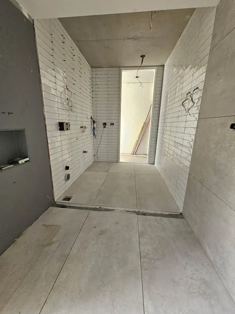 Bathroom mid-renovation with white wall tiles and a large-format floor