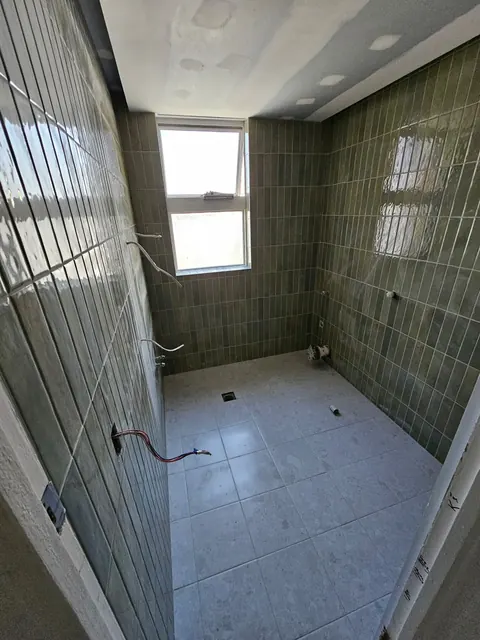 Sage green vertical tile shower during installation